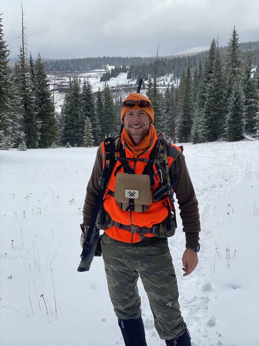 Toby in blaze orange with his rifle in the snow